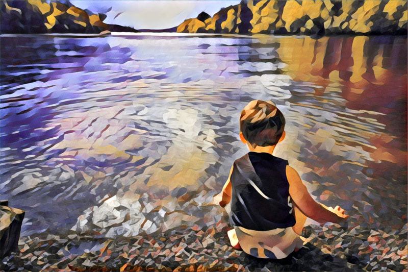 Toddler squatting at the edge of a river.