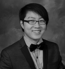 Woman originally from Hong Kong with short black hair, glasses, wearing a suit jacket, button down shirt and bowtie. Photo is black and white. 