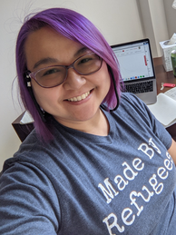 Woman with purple bob and glasses wearing a t-shirt that reads, 