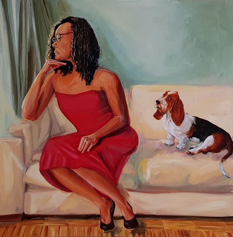 Woman with dark hair, wearing strapless red dress, seated on cream-colored couch next to a beagle.